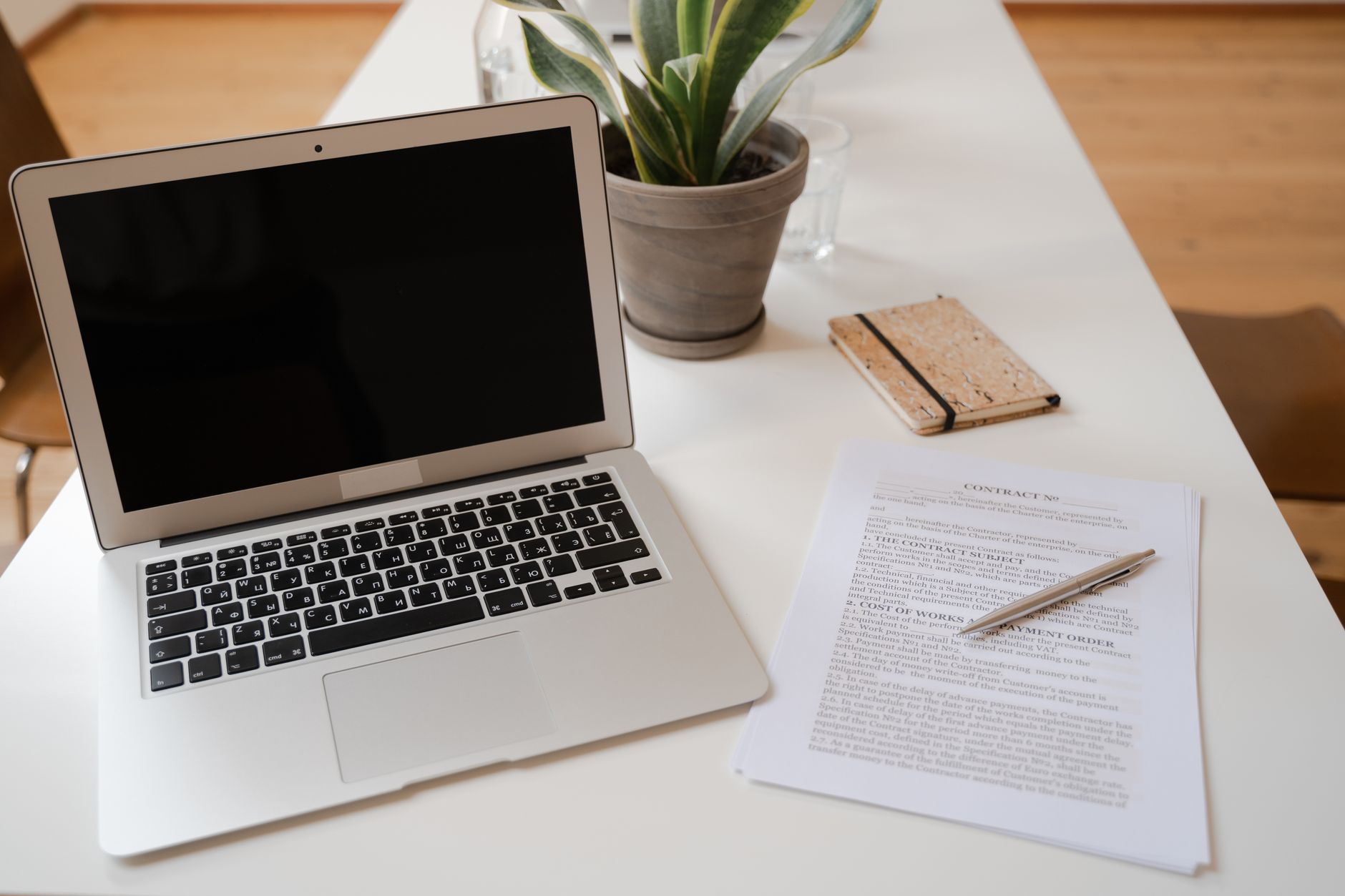 Laptop i umowa na biurku w spokojnym biurze, roślina obok