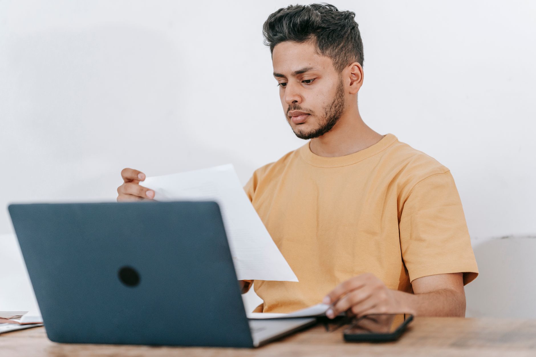 Student z brodą czyta dokument przy laptopie podczas nauki online