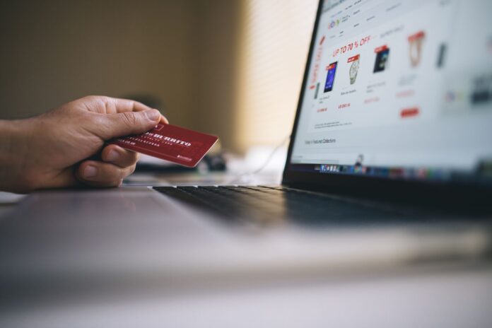 Osoba trzyma kartę płatniczą podczas zakupów online na laptopie Osoba trzyma kartę płatniczą podczas zakupów online na laptopie